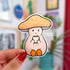 A die cut sticker of a pale mushroom character. His mushroom hate is a warm yellow with white spots. He is happily eating a sandwich. 