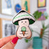A mushroom character sticker with a black, grey, white, and green striped cap holds a green ice cream cone.