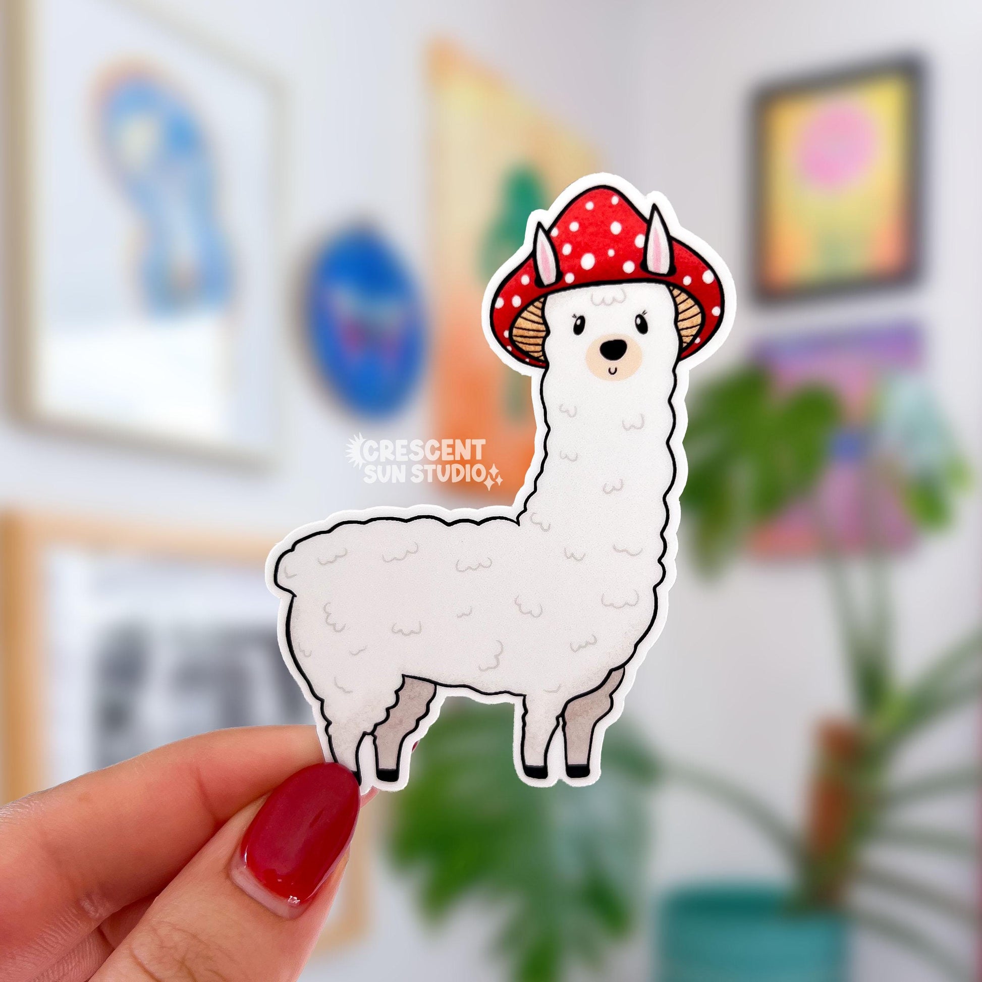 A die cut sticker of a white alpaca wearing a red mushroom cap