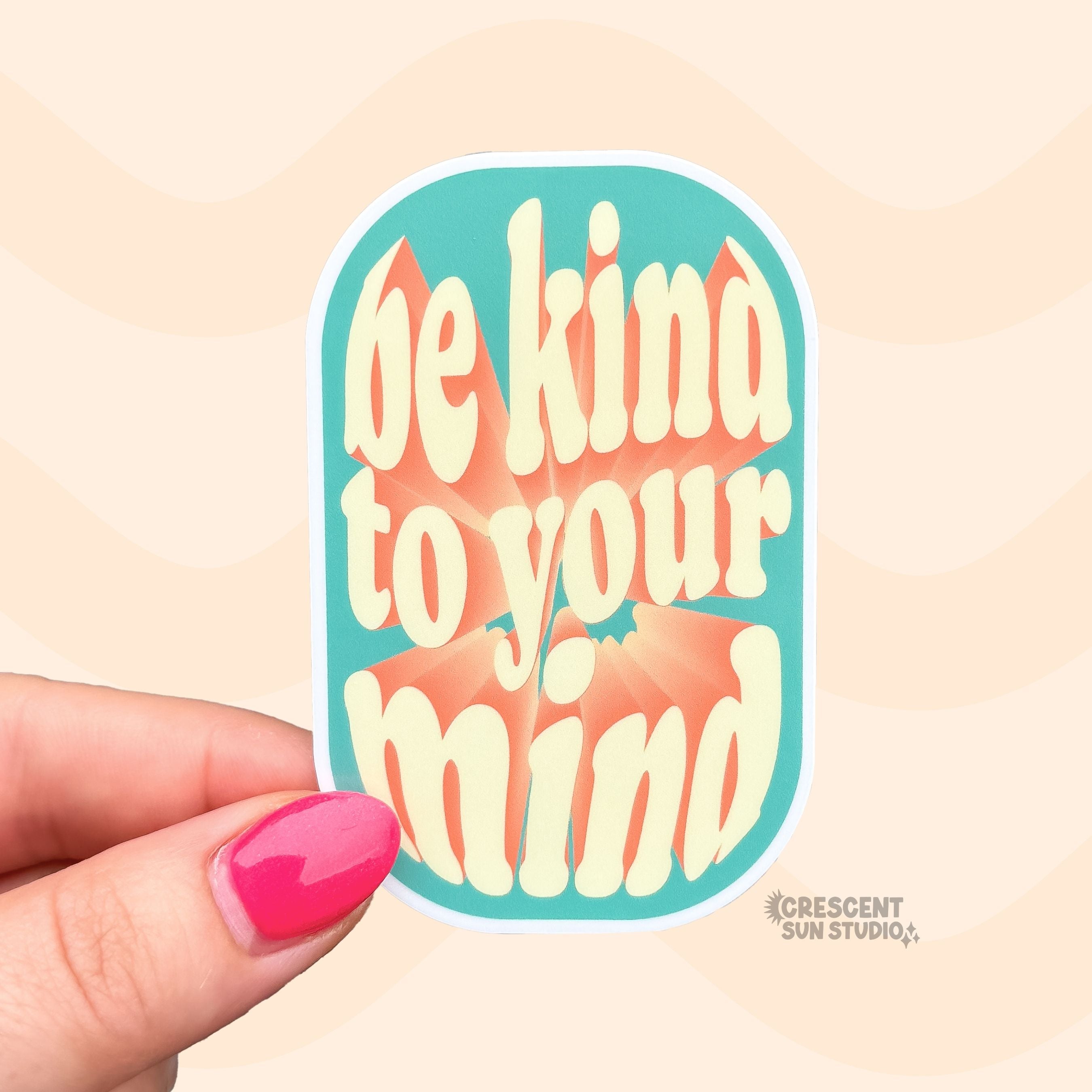 Die-cut sticker with a teal rounded rectangle background reading 'be kind to your mind' in cream retro lettering with an orange accent