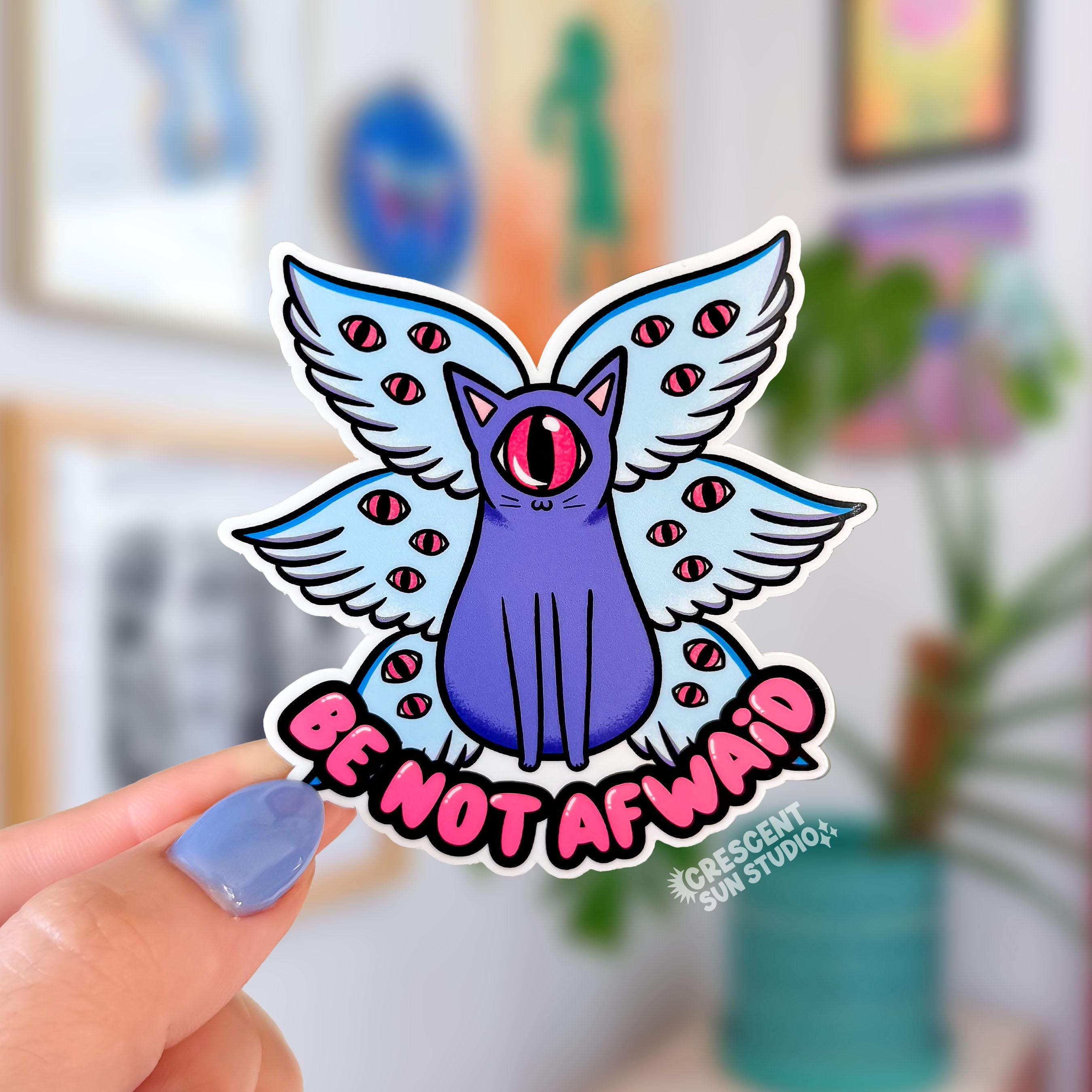 A purple cat with one large pink eye at the center of its face stoically observes you. The cat has three pairs of light-colored angel wings, each wing covered with watchful pink eyes. Underneath the cat, there is pink bubble text that reads: Be Not Afraid.