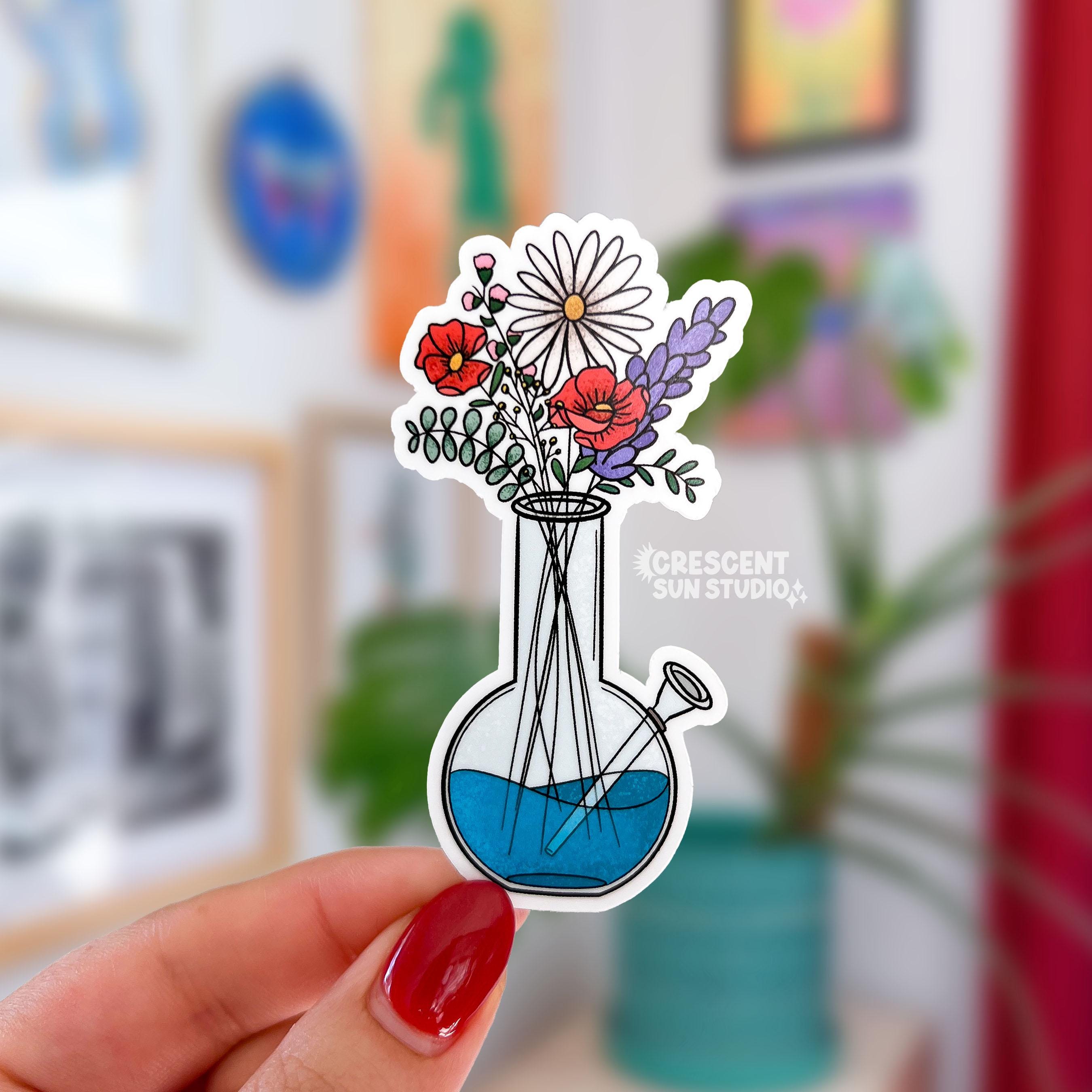 a die cut sticker of a bong with blue water being used as a vase for a variety of wildflowers