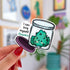 Die-cut sticker of a smiling cannabis nug in an open glass jar with a purple lid, with the text 'I can buy myself flowers' in black and teal lettering.