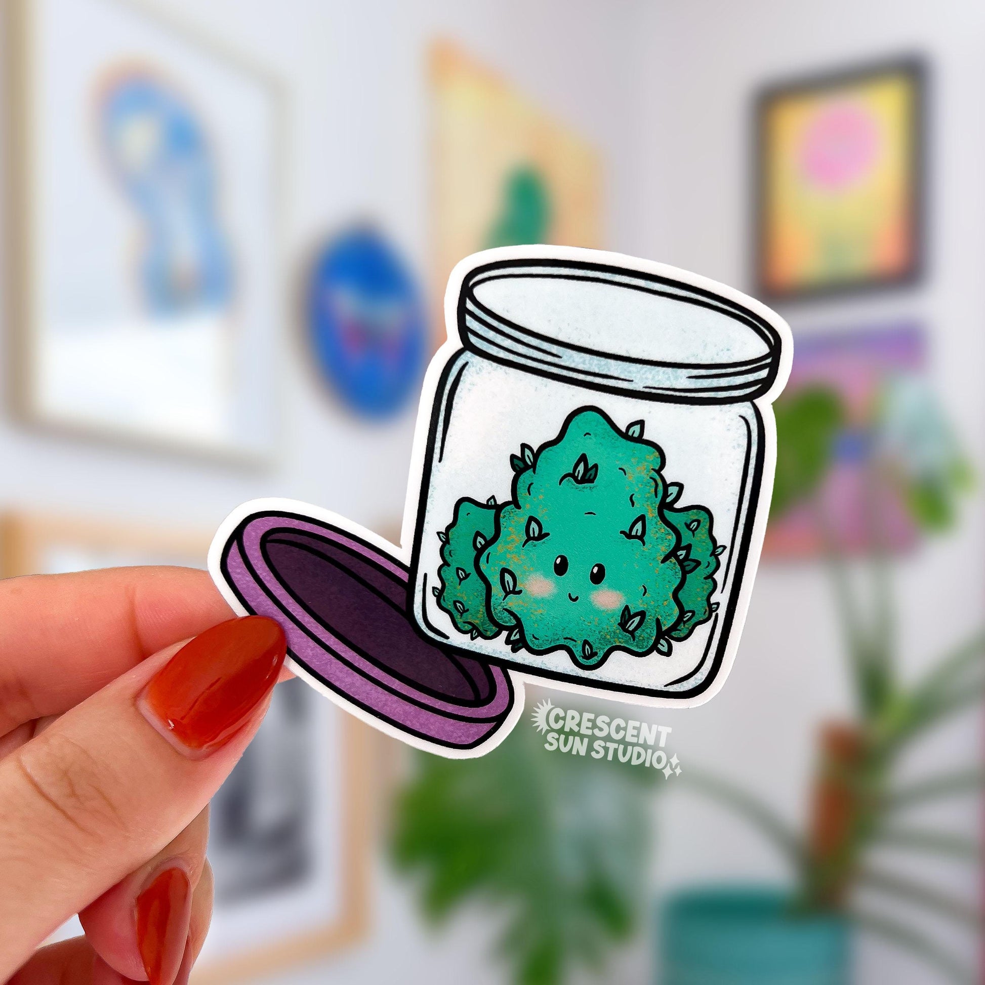 Die-cut water-resistant sticker of a smiling cannabis nug sitting inside an open glass jar with a purple lid.
