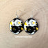 This image depicts a pair of round dangle earrings. On each earring is a black cat and a white cat curled up in a ying yang symbol. The black cat has a yellow crescent moon between her eyes and the white cat has a sun symbol between her eyes. Both smiling cats have two paws pointed outward, so you can see their pink toe pads.
