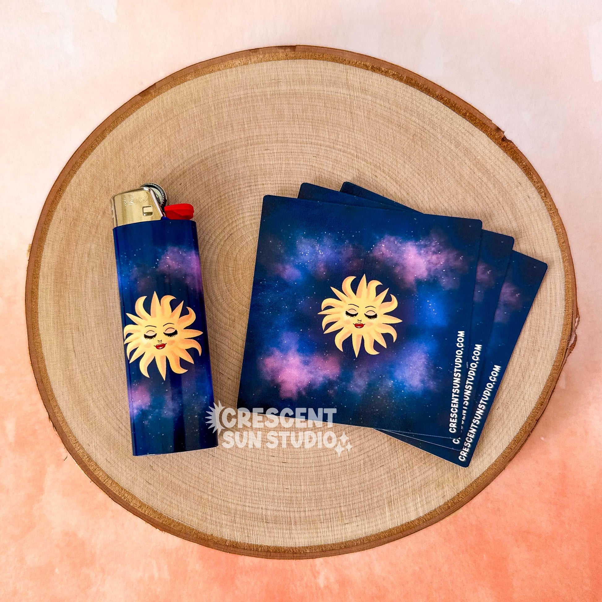 This lighter wrap features a blissed out and elevated glam sun floats in a purple-blue galaxy background. This personified sun has thin eyebrows, closed eyes with full lashes and eyeshadow, a nose ring, blushing cheeks, and glossy full lips.

This image shows a lighter wrapped in the sun design, as well as it looks like before wrapping on a lighter. The product comes to you in a square that is then wrapped around your lighter of choice.
