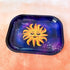 This rectangle tray with raised edges, features a blissed out and elevated glam sun floats in a purple-blue galaxy background. This personified sun has thin eyebrows, closed eyes with full lashes and eyeshadow, a nose ring, blushing cheeks, and glossy full lips.

This image is shot at an angle.