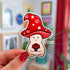 This sticker is shaped like a happy mushroom character whose cap is shaped like a red wizard's hat holds a d20 die.