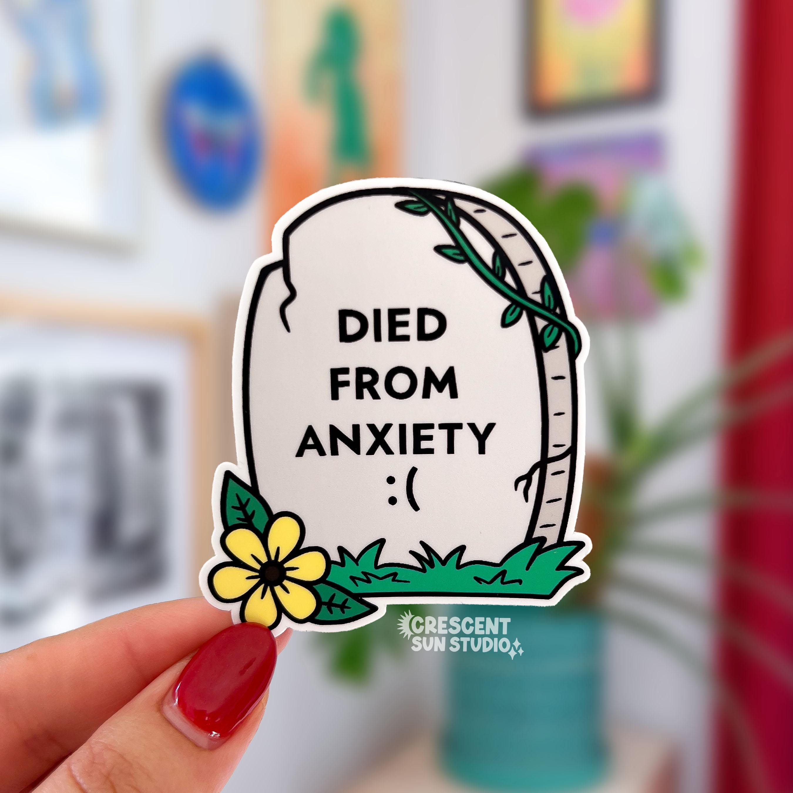A light grey tombstone shaped sticker reads "died from anxiety :(" with a yellow flower in the bottom left corner.