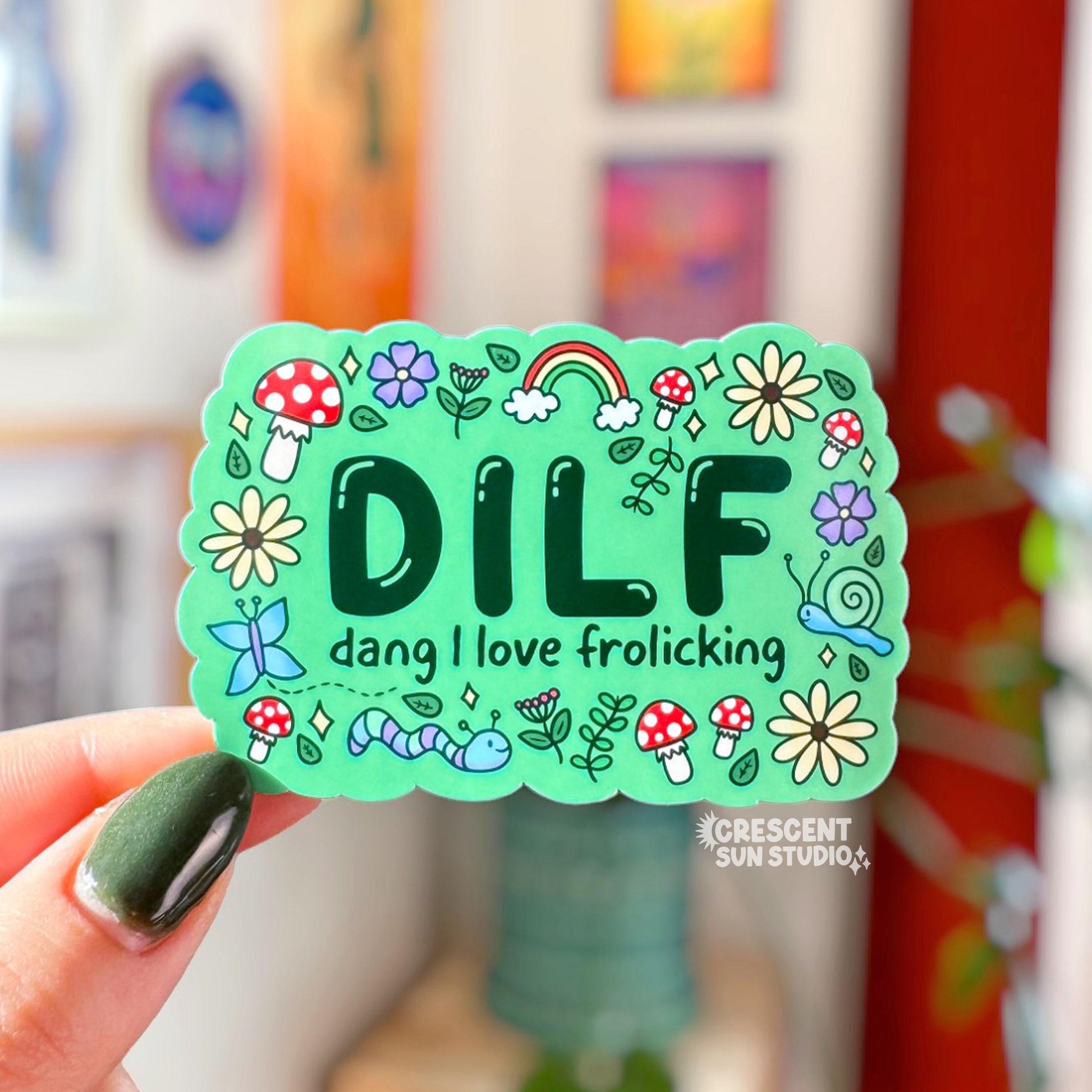 Colorful rectangle-shaped sticker with 'DILF man I love frolicking' text surrounded by doodles of mushrooms, critters, flowers and leaves.