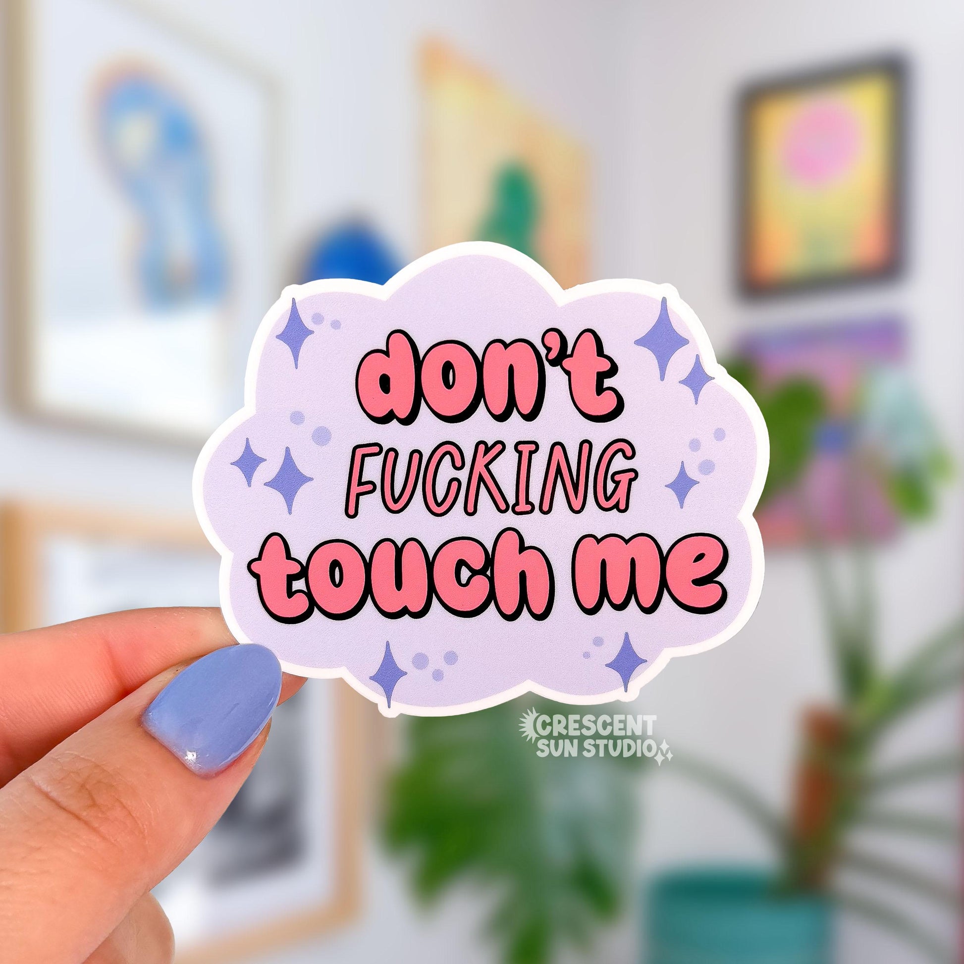 a pastel purple cloud-shaped sticker reads "don't fucking touch me" in pinky coral bubble letters. Purple stars are placed around the words.