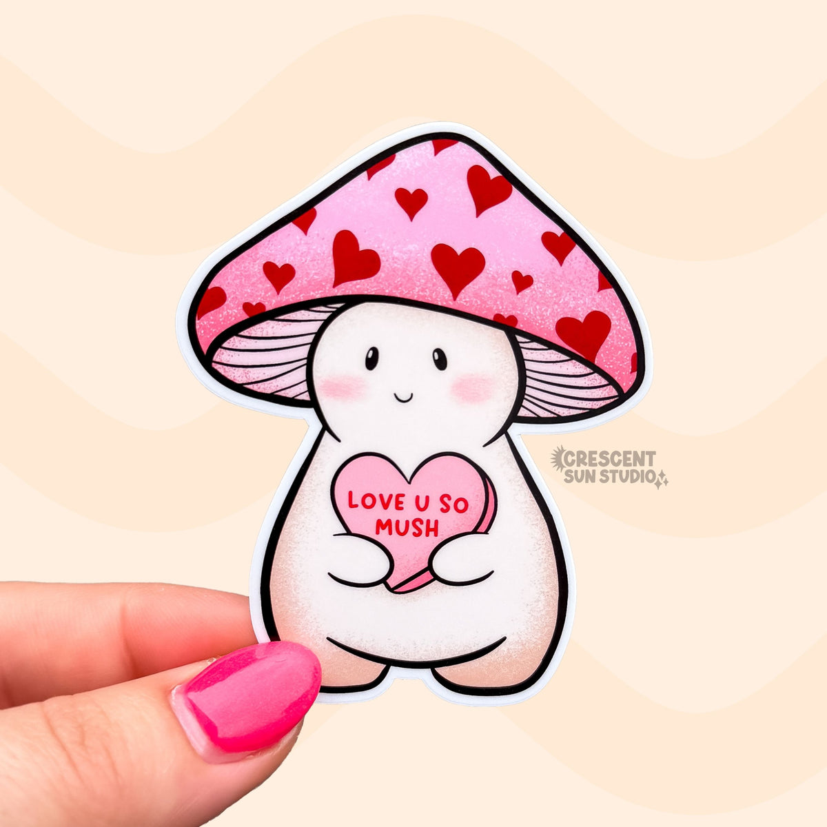 Dovey is a happy and plump cream mushroom character wearing a pink cap with red hearts. They are holding a pink candy heart that reads "Love U So Mush" in red lettering.