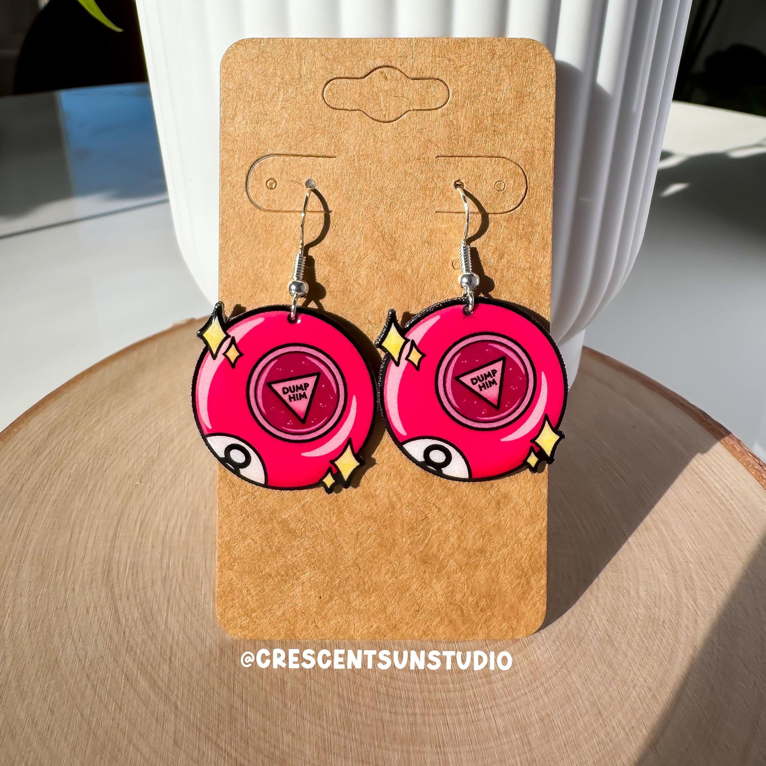 This bright pink pair of 8 ball inspired earrings say "dump him" in the center of the ball. There are also two sets of stars on either side of each ball and part of the letter 8 is visible at the bottom left of, as if curving around the side.