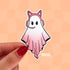 A sticker in the shape of a ghost wearing a pink cat ear headset. Her body is in a gradient pink and white.