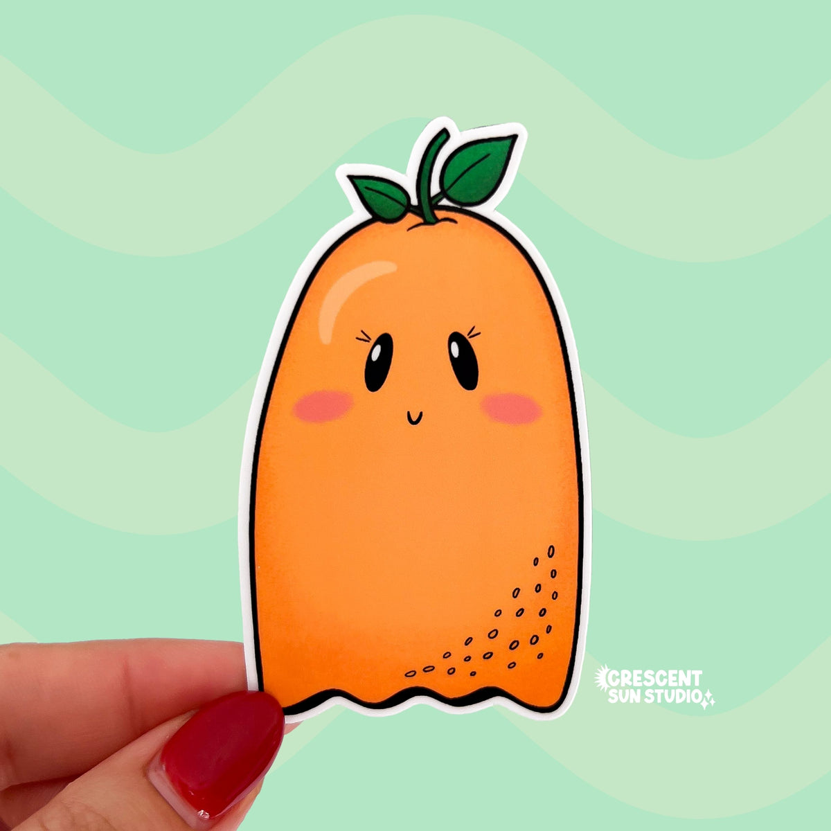 a die cut sticker in the shape of a ghost with a stem on its head is orange in color and has pink cheeks.