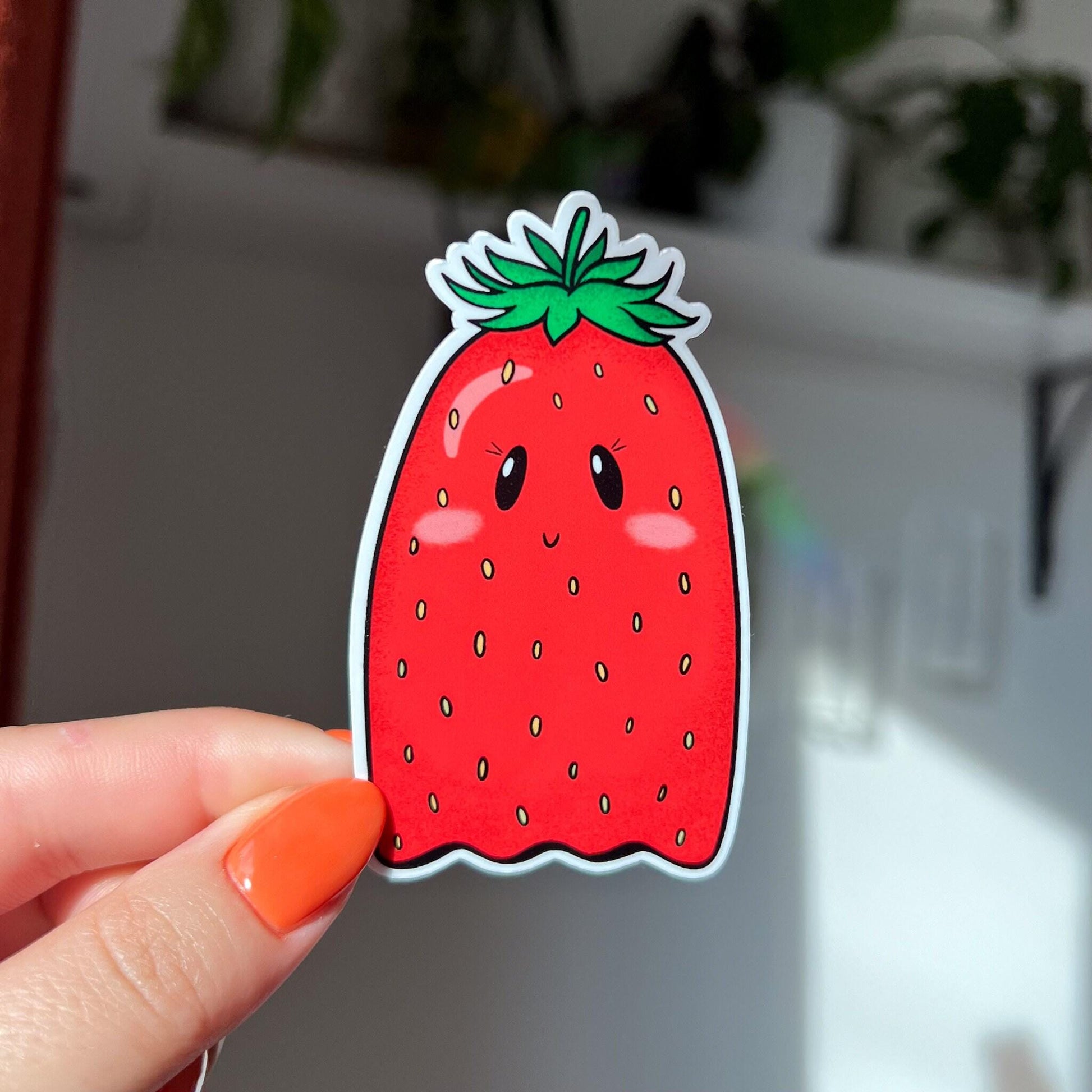 Die-cut sticker of a kawaii strawberry shaped like a ghost, with small eyes, pink cheeks, and a smile.