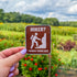 A recreation sign style design features a white pictogram of a hiker climbing. White text on a brown background reads, "Hiker? I hardly know her." 