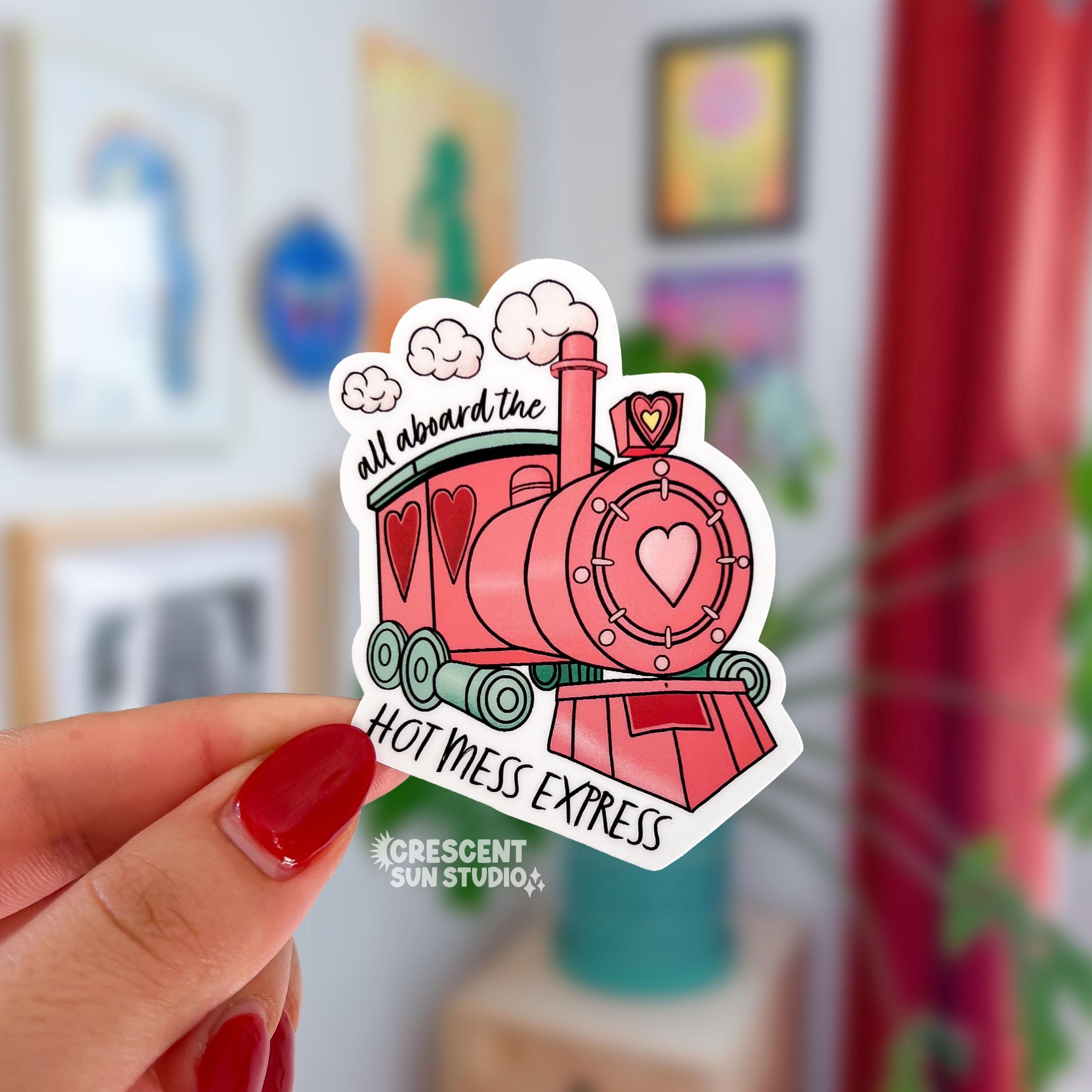 Sticker of a pink and green train with heart accents has the words "all aboard the" on the top and "hot mess express" on the bottom.