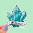A sticker in the shape of three turquoise shaded crystals. At the bottom is a white banner with black text that reads "I attract abundance"
