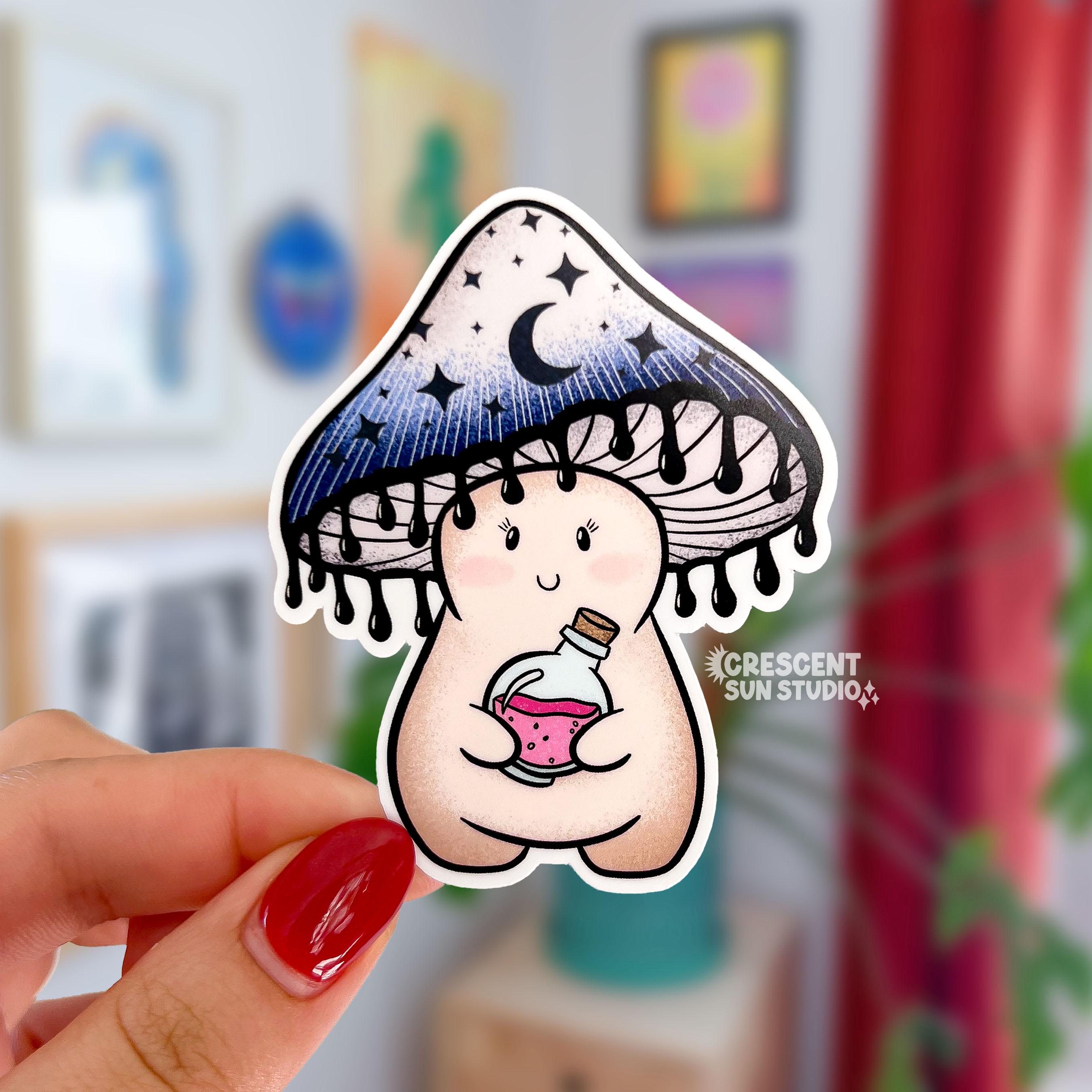 A sticker cut in the shape of a happy little mushroom character. Her mushroom cap is shaded blue-black with dark moons and stars on it. The bottom of the cap has little drips, resembling ink. She is holding a potion bottle with pink liquid inside.