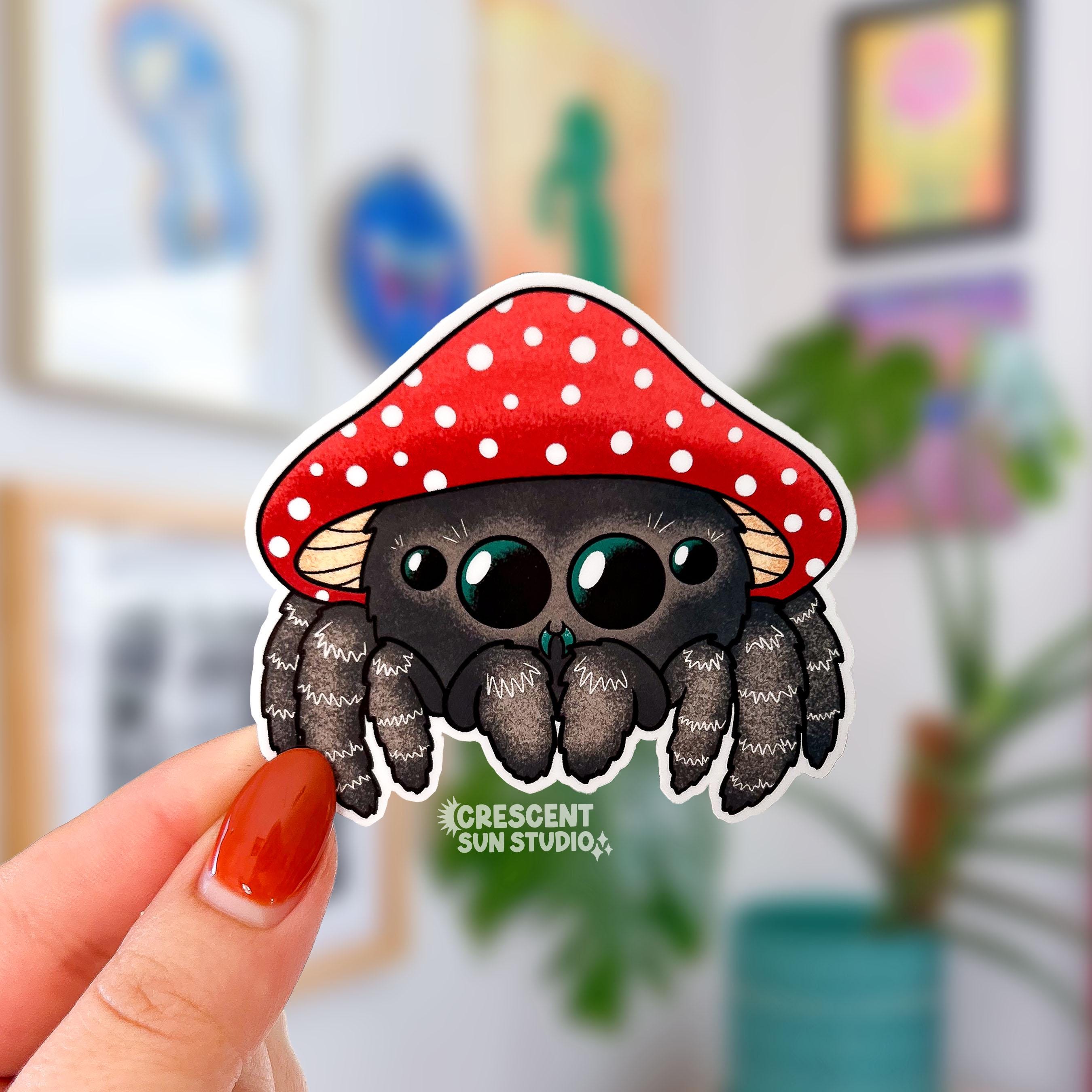A kawaii brown jumping spider wearing a red and white mushroom cap for a hat