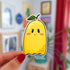 Imagine a sticker in the shape of a ghost, but also a lemon! With a little green leafy stem atop its yellow body, this ghost has a subtle smile, rosy cheeks, and eyelashes.