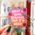 Die-cut sticker with a pink to orange gradient background reading 'What a Long Strange Trip It's Been' in white lettering surrounded by illustrated mushrooms, flowers with eyes, snails, a butterfly, and a worm.