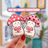 Die cut stickers of two light colored mushroom characters wearing pink and red hats with hearts. Each mushroom holds a pink candy heart. One says "mush love 4 u" and the other says "love u so mush"