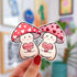 Two stickers of mushroom characters, one with a red cap with white hearts holds a candy heart that says "Mush Love 4 U." The other has a pink cap with red hearts and holds a candy heart that reads "love you so mush"