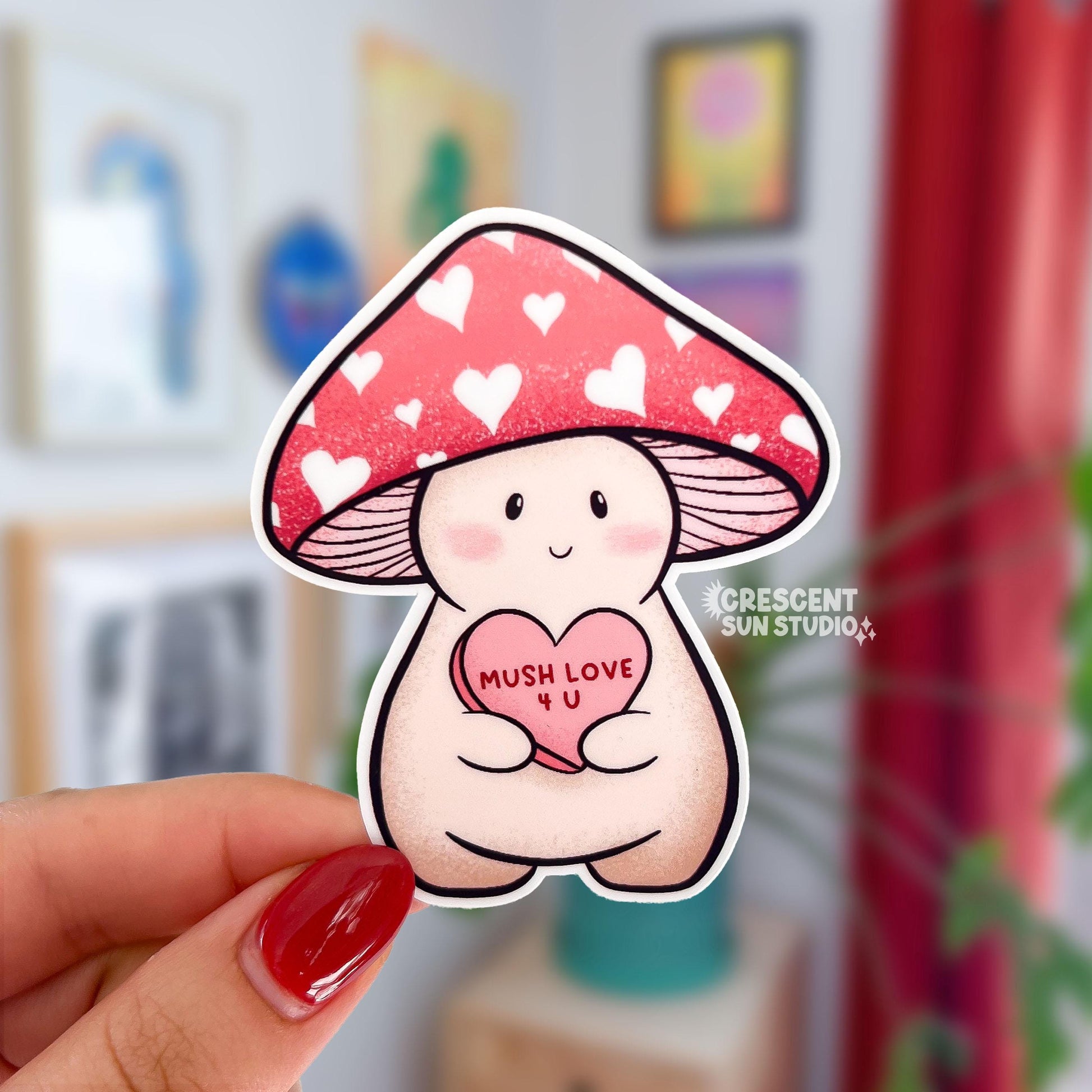 A die cut sticker of Lovey, a happy and plump cream mushroom character with a pink cap covered in white hearts, holding a pink candy heart that reads "Mush Love 4 U." Lovey has some peachy-beige shading around their feet and bottom.
