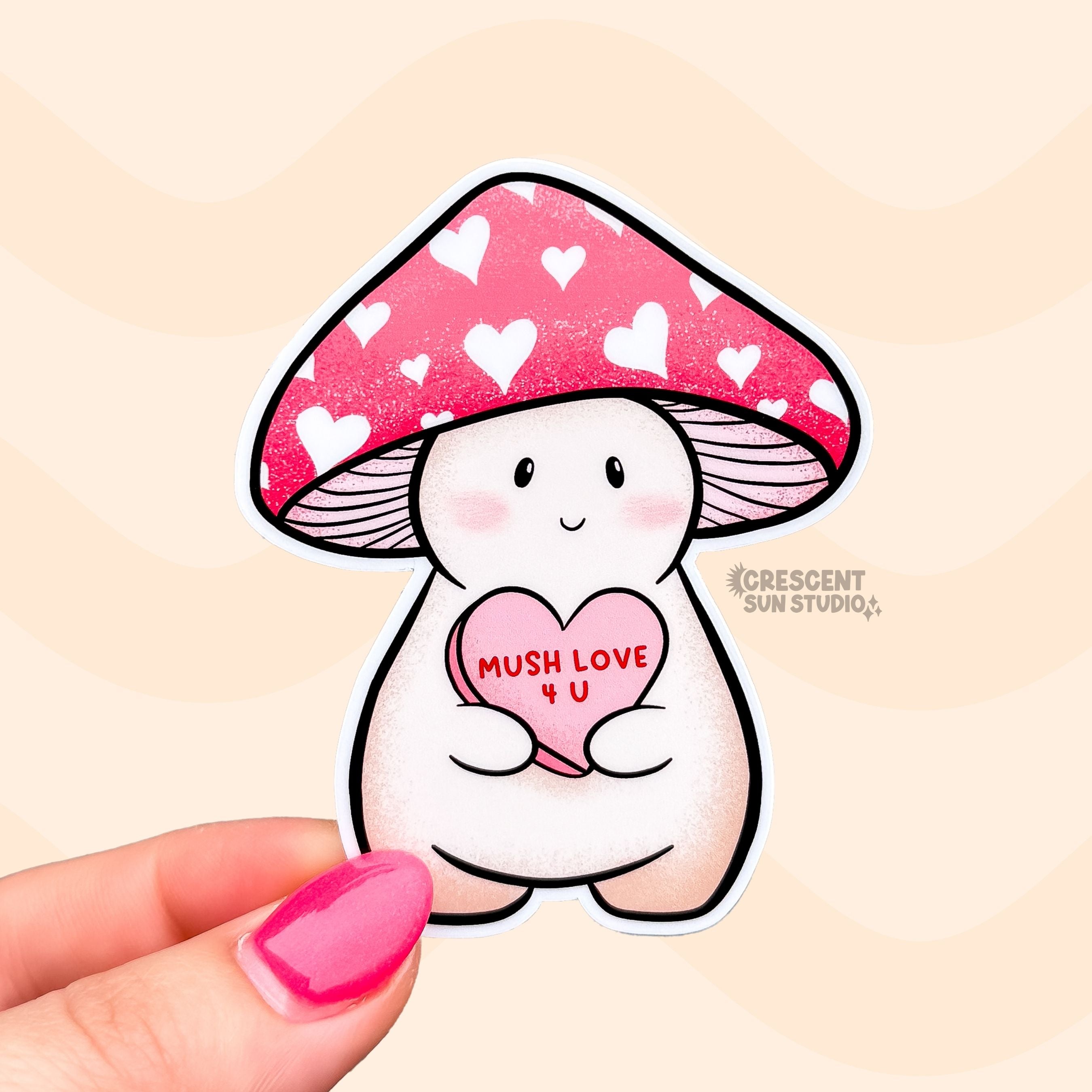 A die cut sticker of Lovey, a happy and plump cream mushroom character with a pink cap covered in white hearts, holding a pink candy heart that reads "Mush Love 4 U." Lovey has some peachy-beige shading around their feet and bottom.