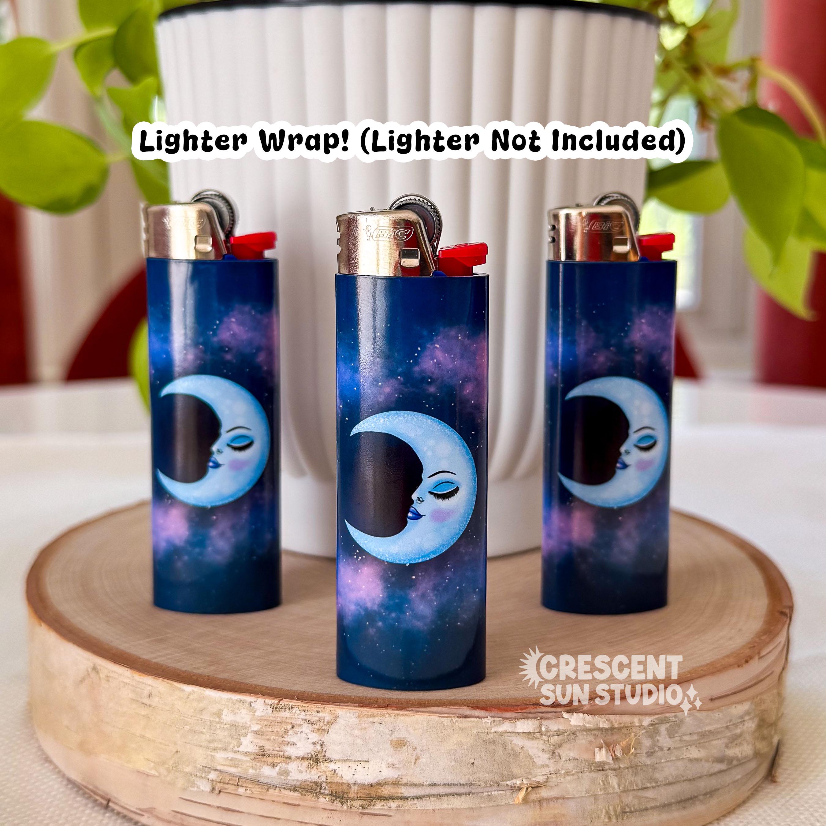 Image shows lighter wraps already applied to three lighters. The background of the wraps are a deep blue and purple galaxy design. In the foreground is crescent moon shaded blue with the profile of a serene and confident woman's face. The face has a thin arched eyebrow, closed eye with deeper blue shadow and lush lashes. She has flushed cheeks and full lips that are glossy purply-blue.

Text on top of the image reads: Lighter Wrap! Lighter not included