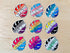 Colorful monstera leaf stickers, each in hte colors of different pride flags, are arranged in three rows of three