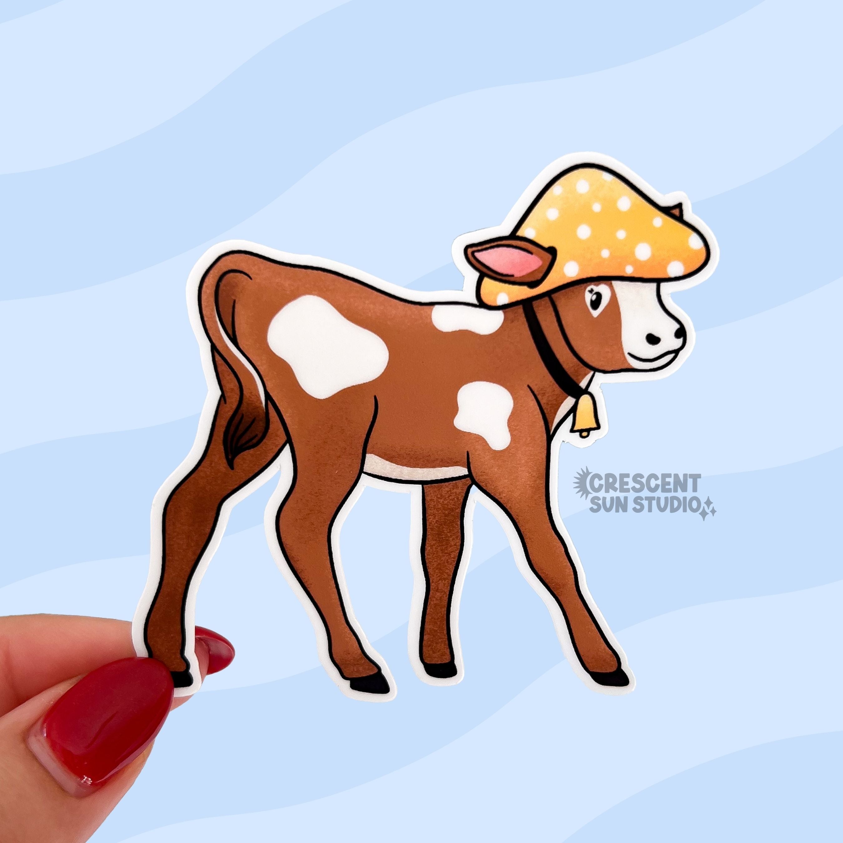 A brown and white baby cow wears a yellow mushroom hat in this die cut sticker.