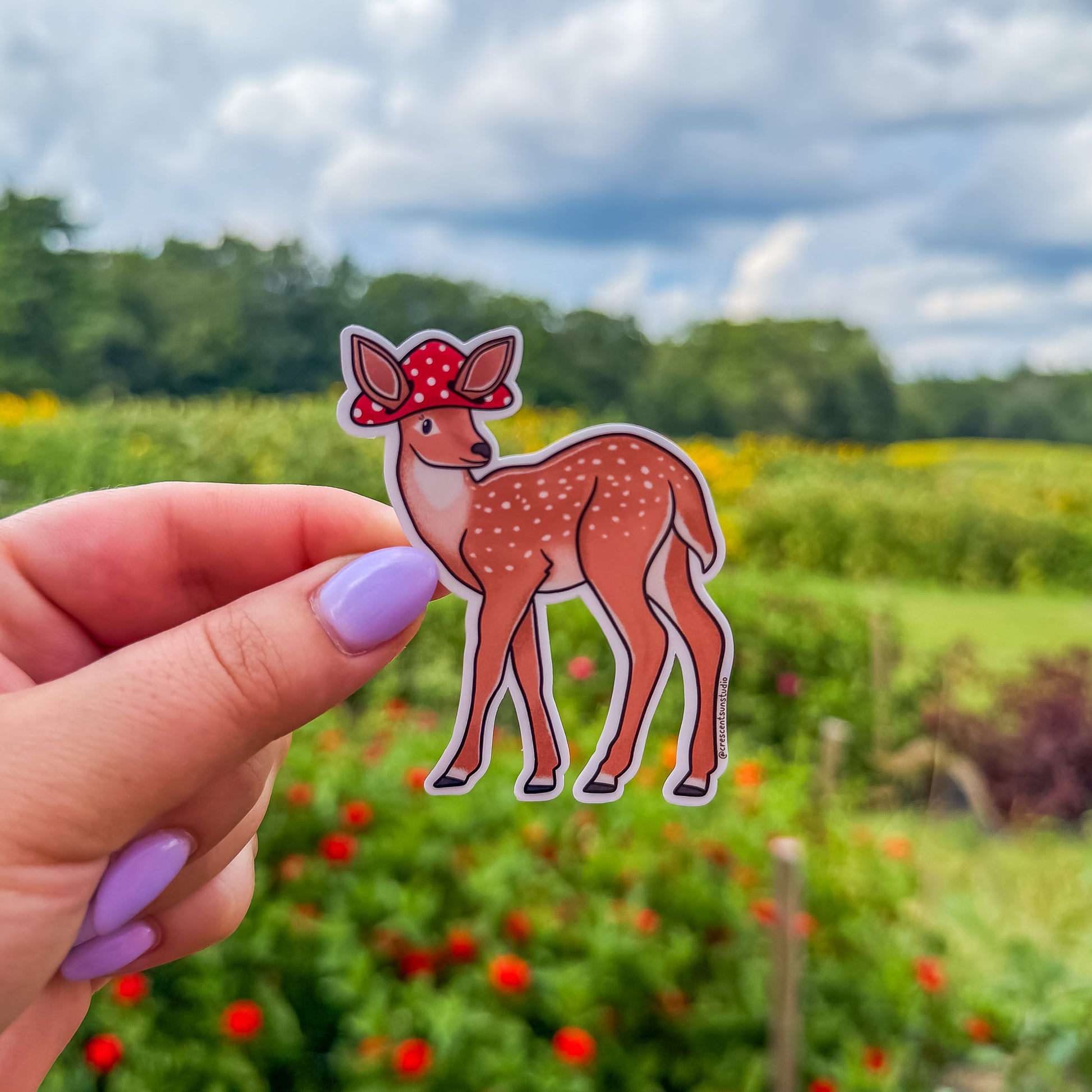 A die cut spotted deer sticker wearing a mushroom cap with cutouts for the deer's large ears.