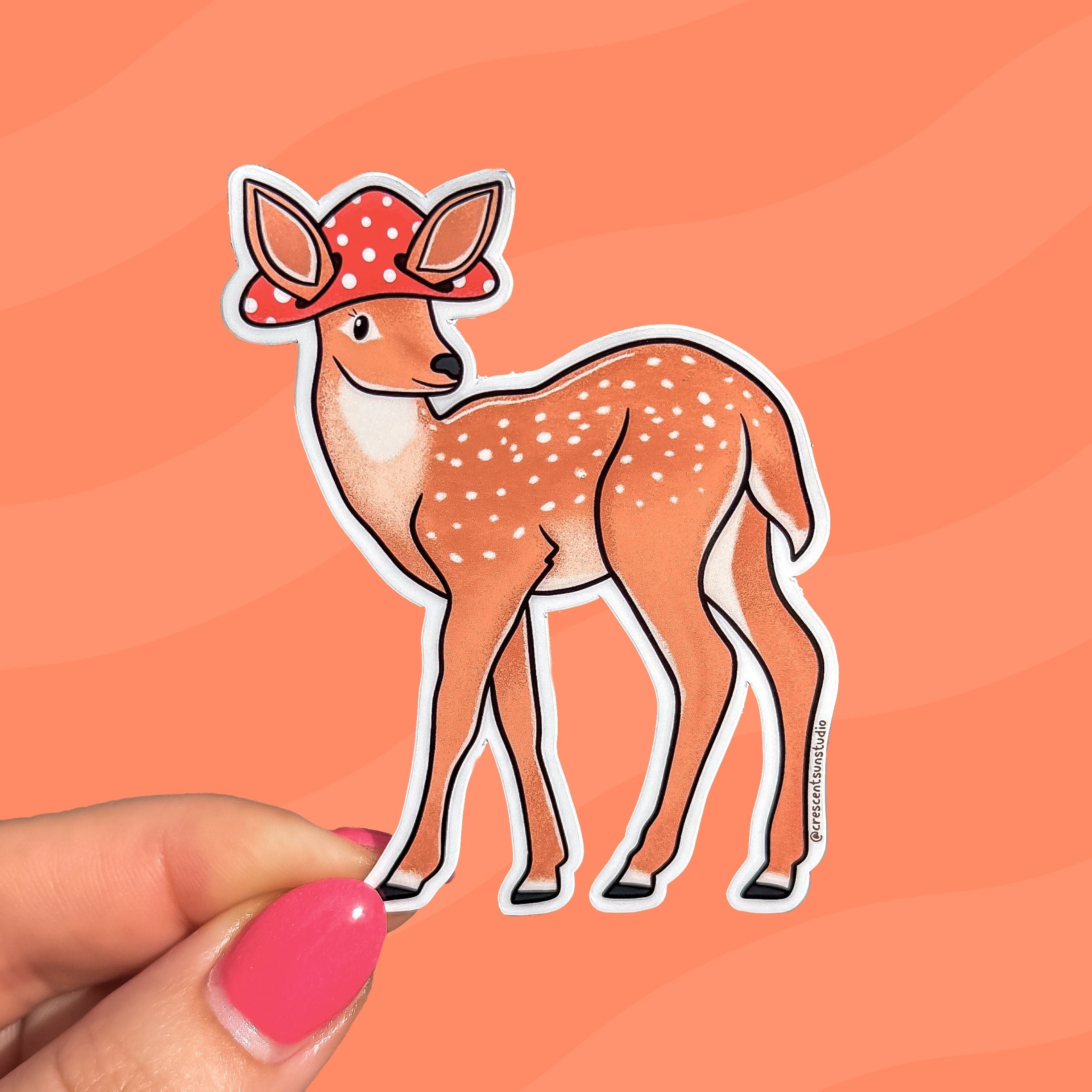 A die cut spotted deer sticker wearing a mushroom cap with cutouts for the deer's large ears.