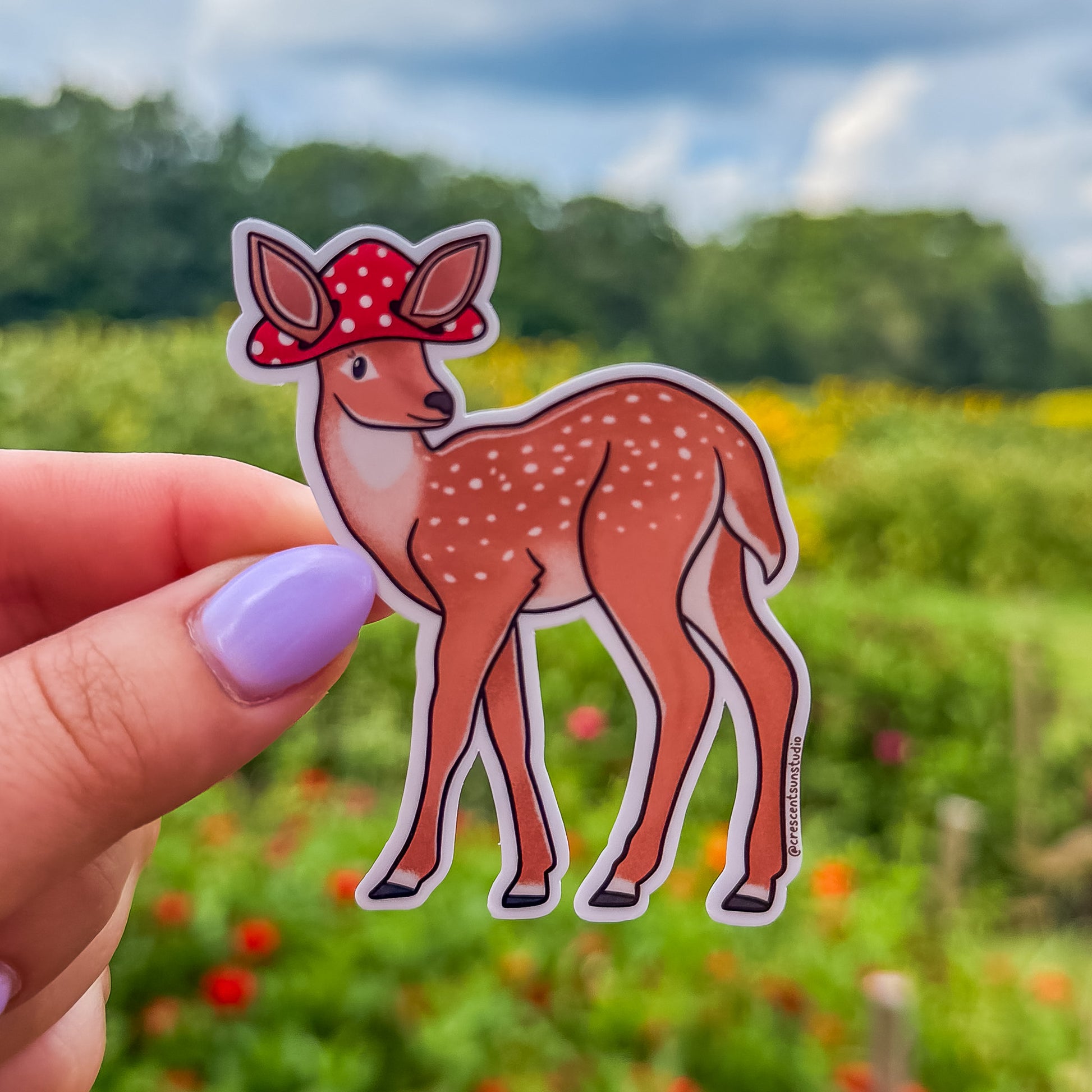 A die cut spotted deer sticker wearing a mushroom cap with cutouts for the deer's large ears.
