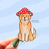 A tan colored golden retriever sticker. The dog sits with his tongue out and wears a red and white mushroom cap.