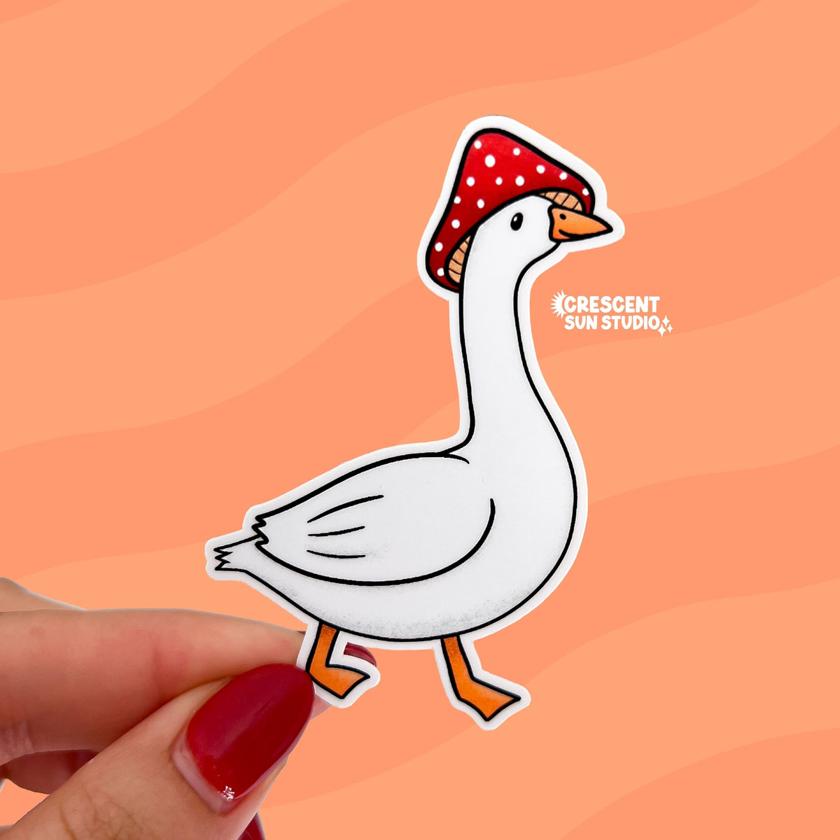 Our goose mushroom sticker features a very silly, but unbothered, white goose wearing a red and white spotted mushroom cap on its head. The sticker shows the white goose's side profile and the bird is also mid-step.