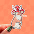 Die-cut sticker of a fluffy brown and white rabbit wearing a red spotted mushroom cap, standing upright with a composed expression.