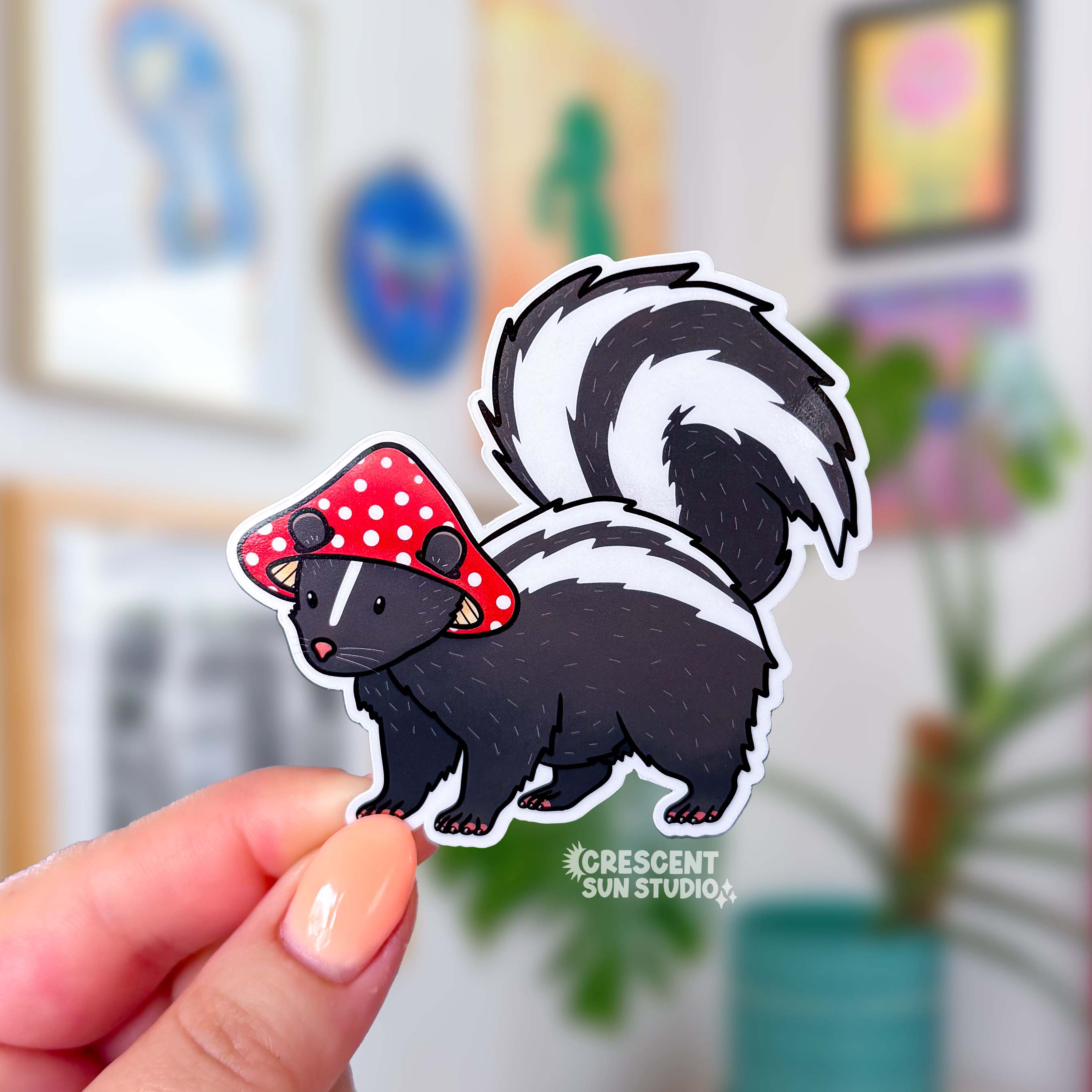 A die cut sticker of a skunk wearing a red and white mushroom cap for a hat.