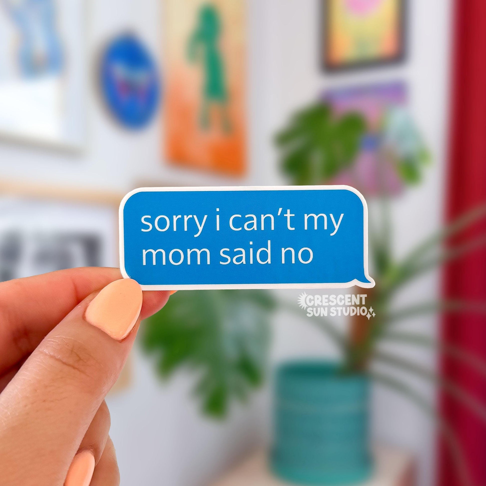 a die cut sticker in the shape of a blue chat bubble says "sorry I can't my mom said no" in white lettering.