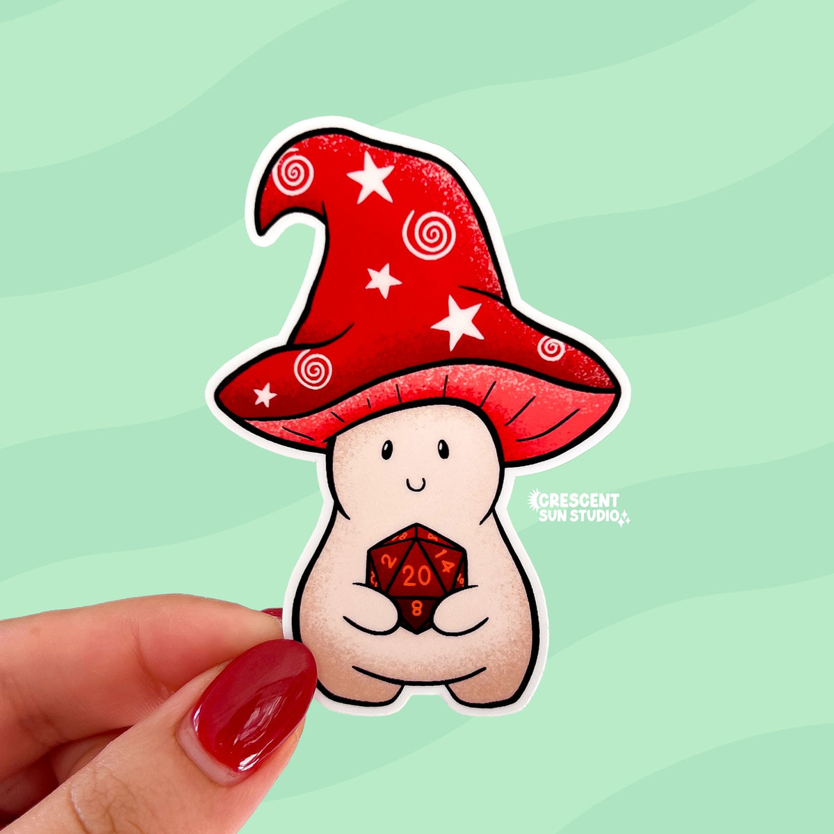 This sticker is shaped like a happy mushroom character whose cap is shaped like a red wizard's hat holds a d20 die. He rolled a nat 20.