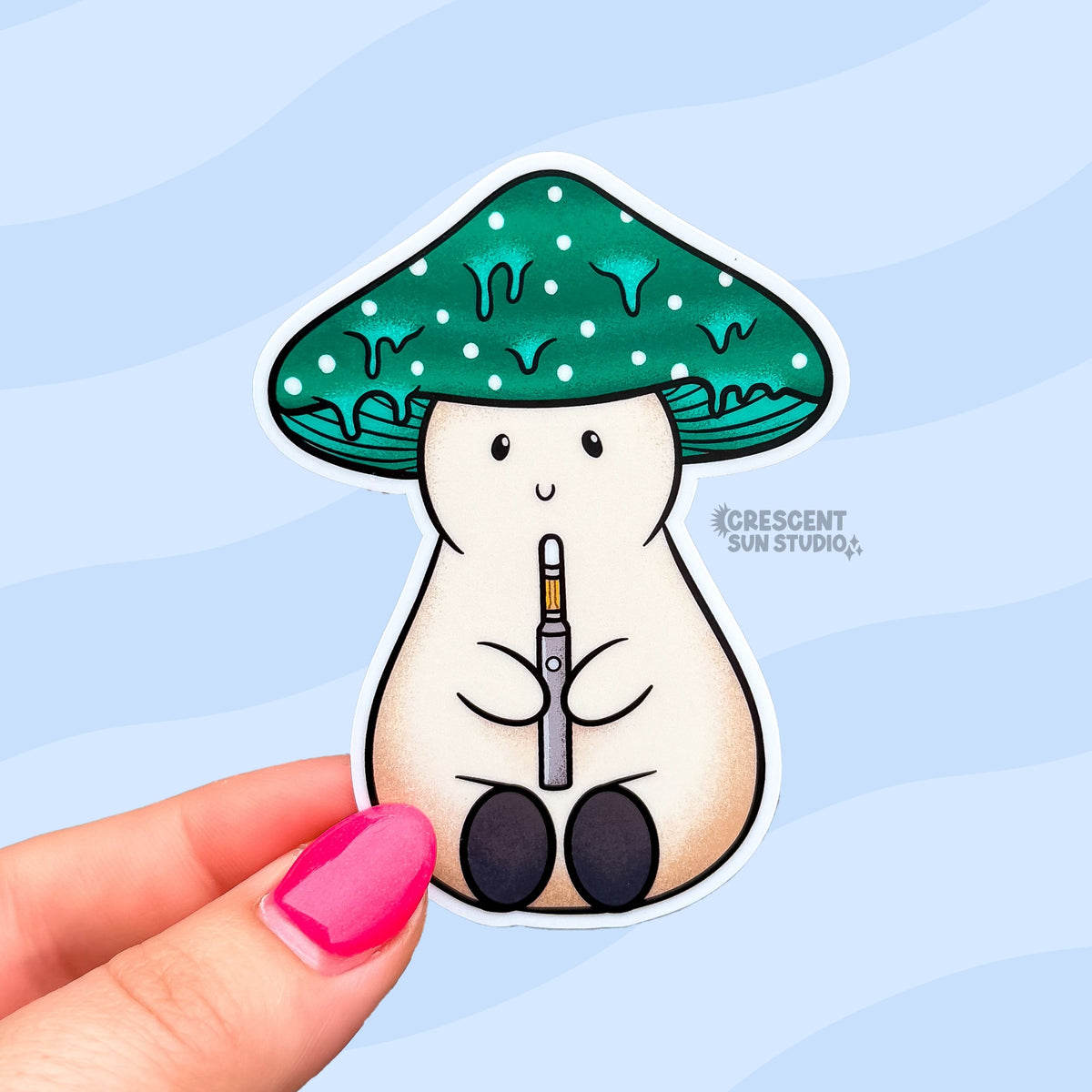 A sticker in the shape of a beige plump mushroom character with a dark teal dripping cap with white spots, holding a dab pen. The mushroom has a smiling face.