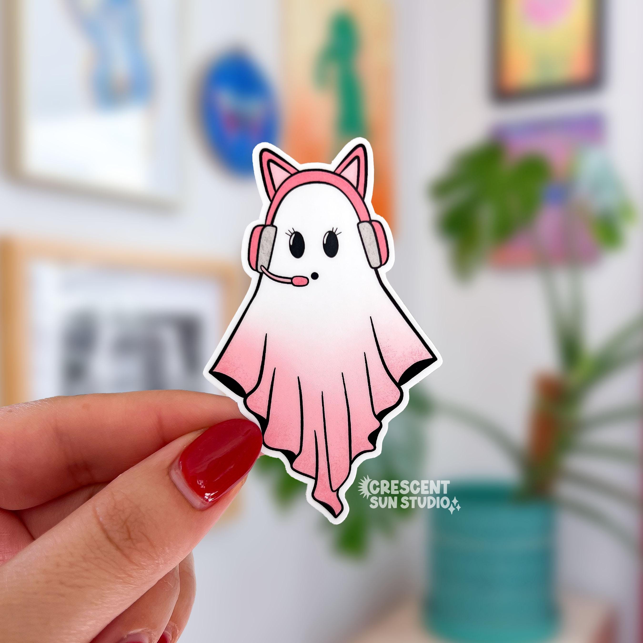 A sticker in the shape of a ghost wearing a pink cat ear headseat. Her body is in gradient pink and you can tell she is involved in an intense conversation