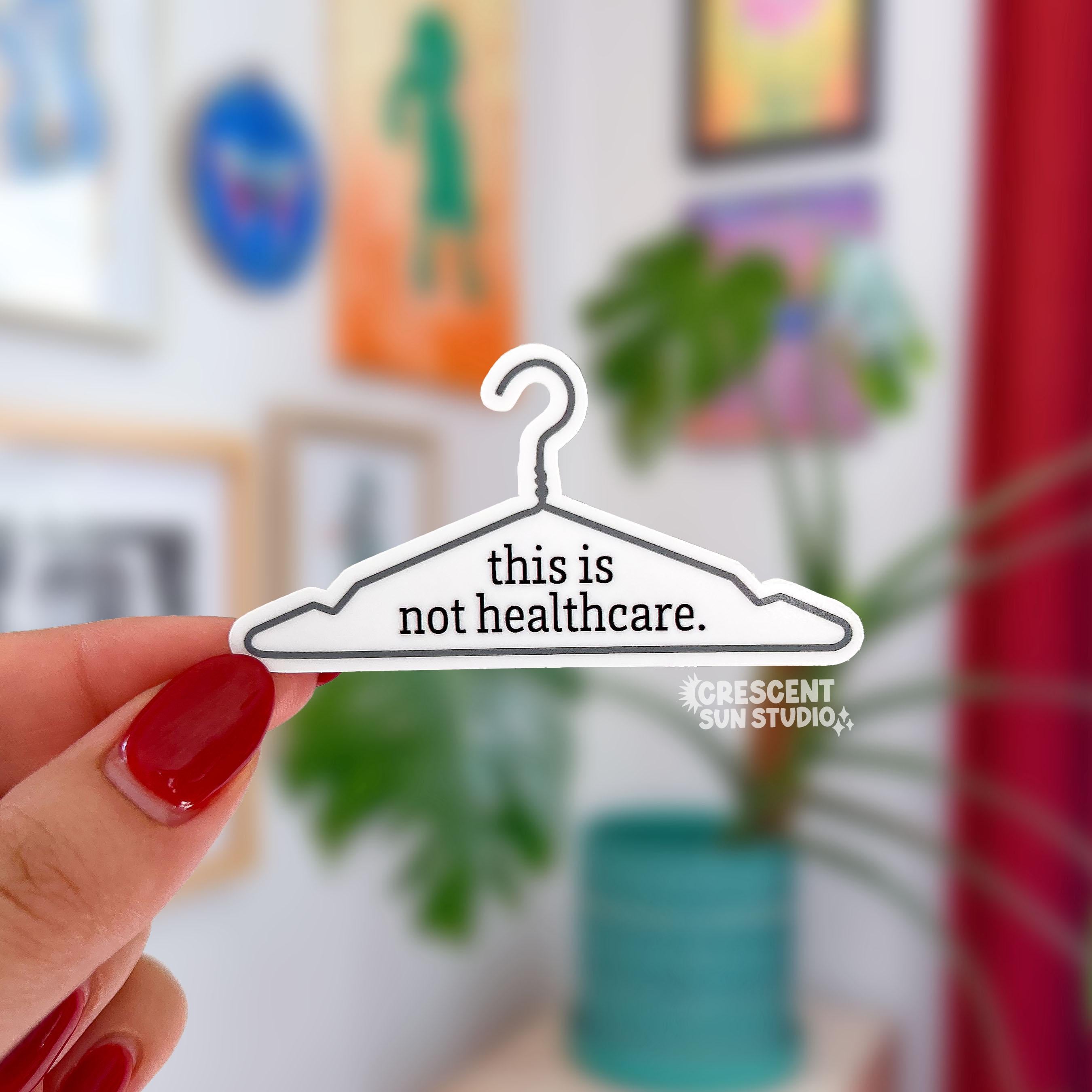 A die cut sticker of a wire hanger. In the center reads the text "this is not healthcare"