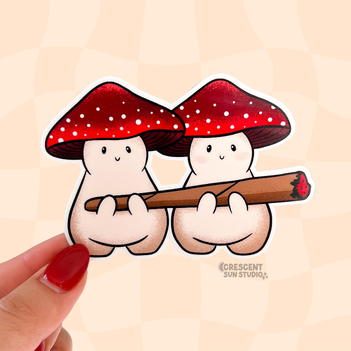 Die cut sticker of two plump beige mushroom characters with red and white spotted caps, sit side by side sharing a lit blunt.