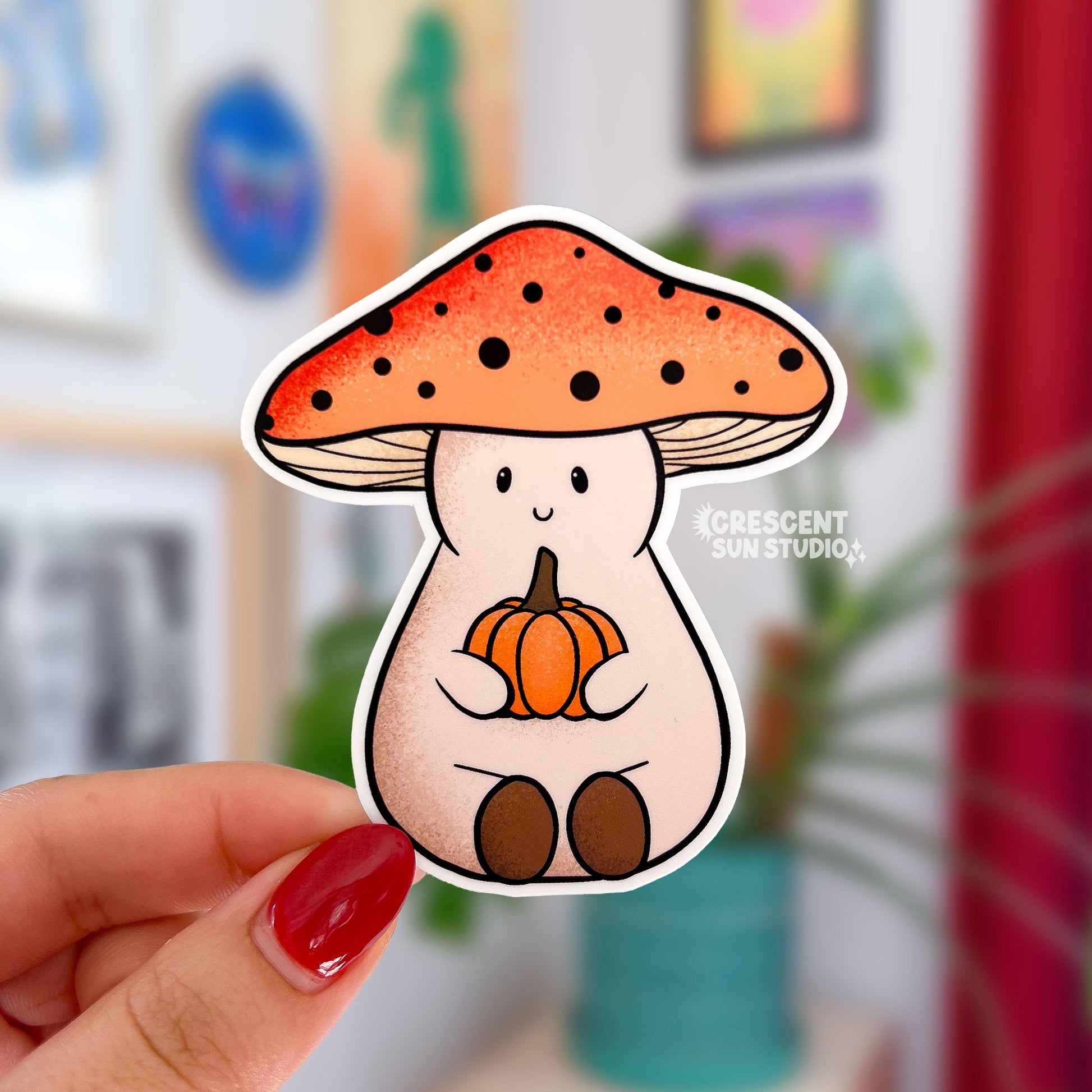 A mushroom shaped sticker of a friendly character wearing an orange mushroom cap and holding a small orange pumpkin