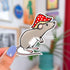 A diecut sticker of a curious gray rat wearing a red and white mushroom cap