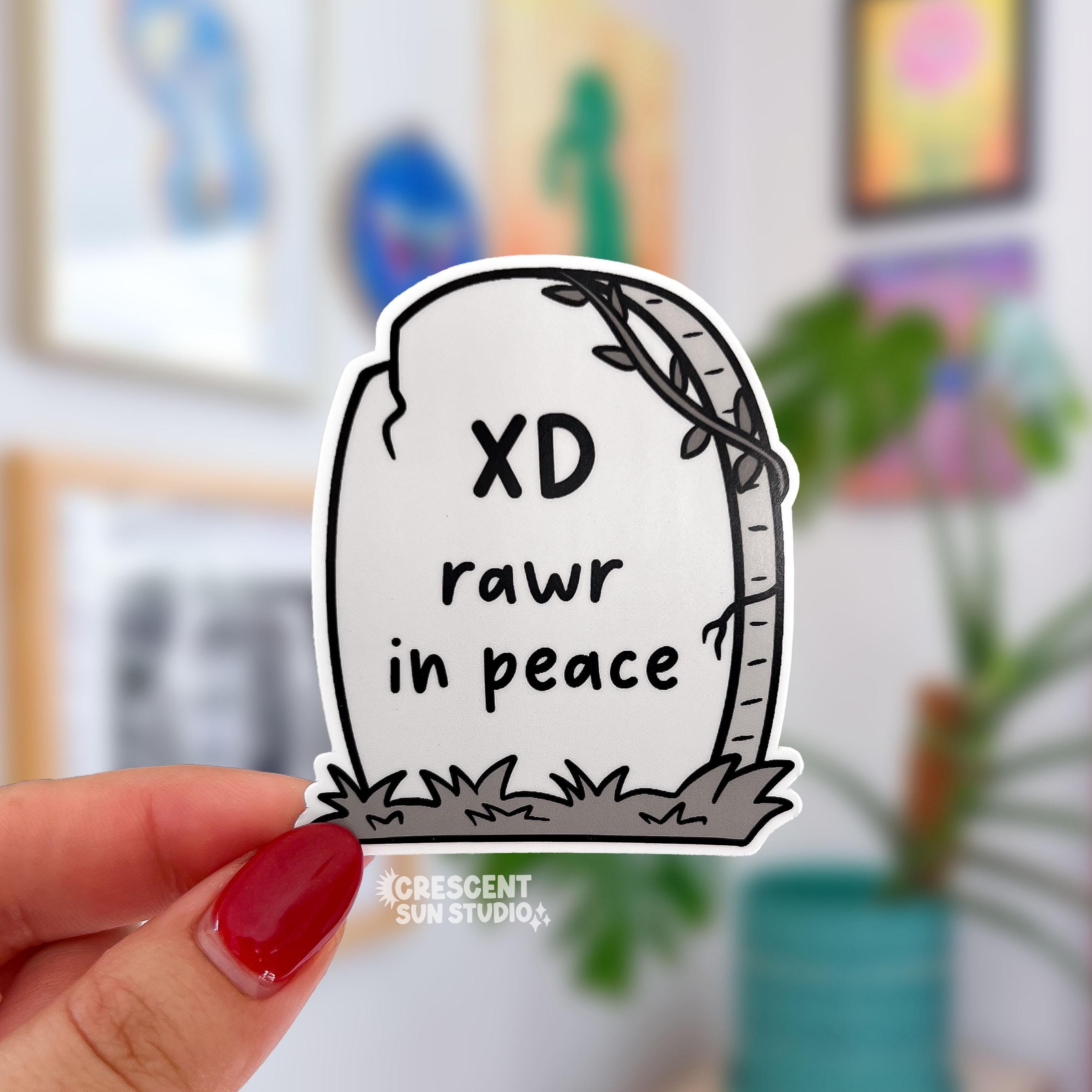 a die cut gravestone sticker with the epitaph "XD rawr in peace"